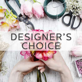 Hands holding a pink flower bouquet with floral tools and supplies nearby