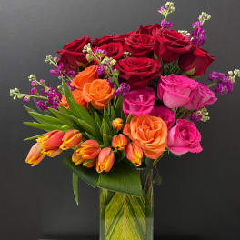 Bouquet of red, pink, and orange roses in a glass vase