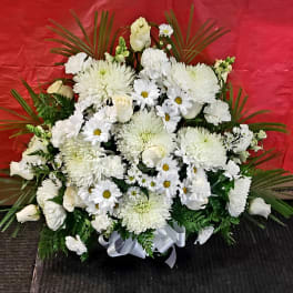 White floral arrangement with daisies and roses in a ribbon-tied base