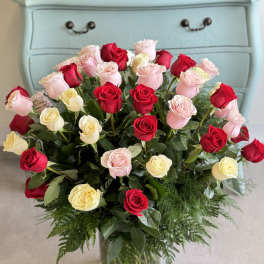 Bouquet of red, pink, and cream roses in a glass vase
