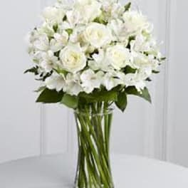 White roses and white orchids in a clear glass vase