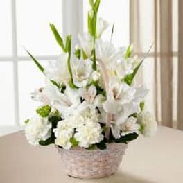 White floral arrangement in a woven basket with tall green spikes