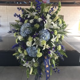 Large standing floral spray with blue, white, and green blooms