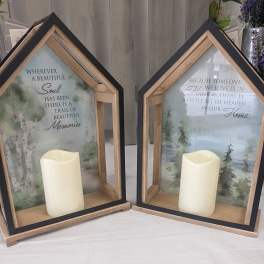 Two house-shaped memorial lanterns with candles and printed sympathy messages