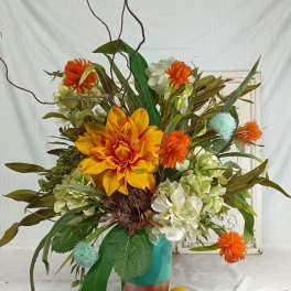 Orange and white floral arrangement in a turquoise vase with decorative branches