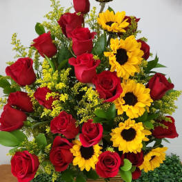 Bouquet of red roses and yellow sunflowers in a woven basket