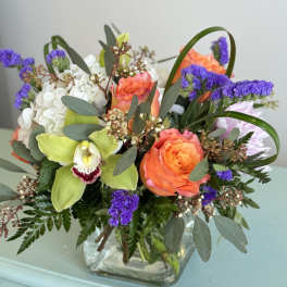 Mixed bouquet in a square glass vase with orange roses and green orchids