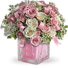 Pink and white rose bouquet in a clear square vase with ribbon