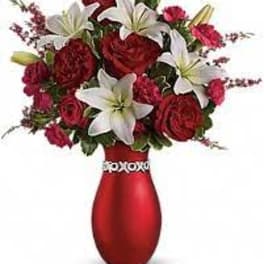 Red and white flower arrangement in a red vase