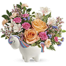 Bouquet of pink and peach roses in a unicorn-shaped vase