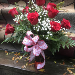Bouquet of red roses with baby's breath in a vase and ribbon