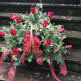Arrangement of red roses with white filler flowers and red ribbon