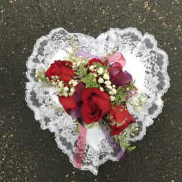 Heart-shaped bouquet of red roses with white lace trim and ribbon