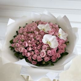 Large bouquet of pink roses with white orchids wrapped in white paper