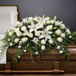 White floral casket spray with lilies and roses