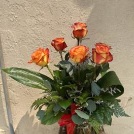 Bouquet of orange-red roses in a glass vase with a red ribbon