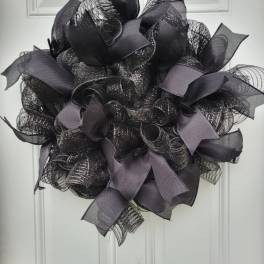 Black mesh wreath with gray ribbon loops on a white door