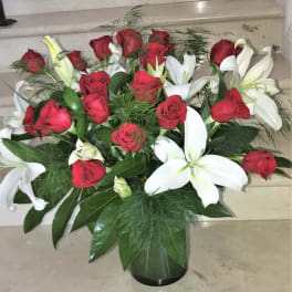 Arrangement of red roses and white lilies in a dark glass vase