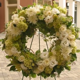 Large wreath of white and green flowers displayed on a metal easel stand
