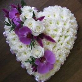 Heart-shaped white floral arrangement with purple orchids and white roses.