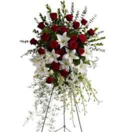 Tall standing spray of red roses and white lilies on a metal easel