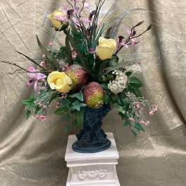 Tall floral arrangement with yellow roses and purple orchids in a dark vase