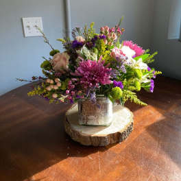 Mixed bouquet in a rustic square vase on a wood slice base