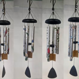 Six hanging metal wind chimes with floral patterns and black tops