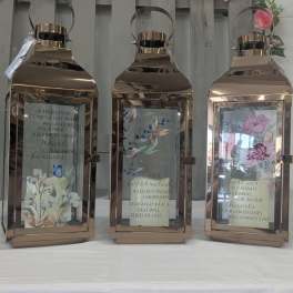Three rose-gold lanterns with floral inserts and memorial quotes