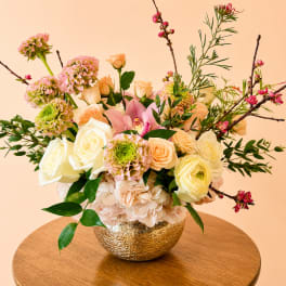 Mixed pastel flower arrangement in a gold bowl vase