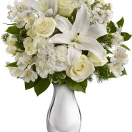 White lilies and roses arranged in a glass vase