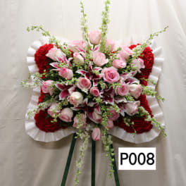 Standing floral spray with pink roses and red carnations on a white easel