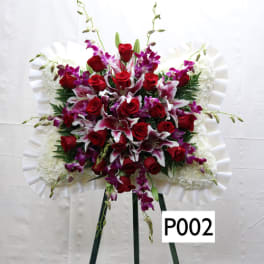 Standing funeral spray with red roses and purple orchids on a white easel