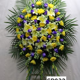 Standing floral spray with yellow and purple flowers on a frame