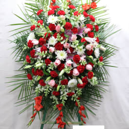 Large standing floral spray with red, pink, and white flowers on a green easel