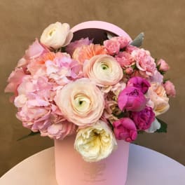 Pink and cream flower arrangement in a round hatbox