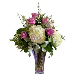 Pink roses and white hydrangeas in a purple glass vase