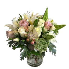 Bouquet of white lilies and pale pink roses in a clear glass vase