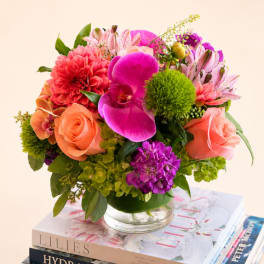Mixed bouquet of pink, coral, and purple flowers in a glass vase
