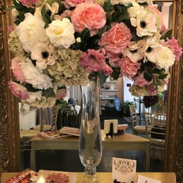 Large pink and white floral arrangement in a tall glass vase