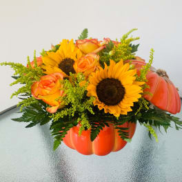 Sunflowers and orange roses in a pumpkin-shaped container