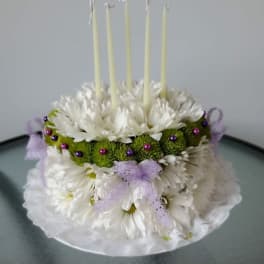 White floral cake with five tall candles and purple ribbon accents