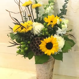 Tall floral arrangement with yellow sunflowers and white blooms in a birch-style vase