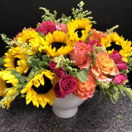 Bright sunflower and rose arrangement in a white vase