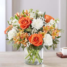 Orange roses and white carnations in a clear glass vase