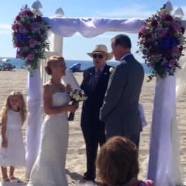 Beach wedding arch decorated with pink and purple flowers