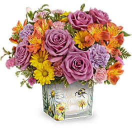 Mixed bouquet of purple roses, yellow daisies, and orange alstroemeria in a square vase