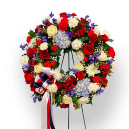 Large floral wreath with red, white, blue, and cream flowers on a stand