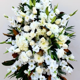 Large white funeral spray with lilies, roses, and chrysanthemums on an easel