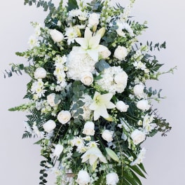 Large white floral standing spray with lilies, roses, and daisies